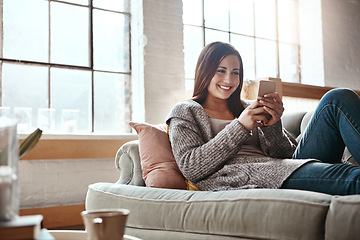 Image showing Phone, woman and relax on a sofa with app, social media and texting in her home, happy and smile. Smartphone, girl and chatting, online dating and internet, search and streaming in a living room