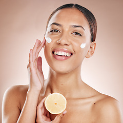 Image showing Face, cream and woman with lemon for natural beauty, cosmetics or healthy glow in studio product advertising. Young model in happy portrait for vitamin c sunscreen, dermatology and facial promotion