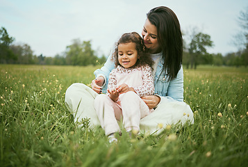 Image showing Children, family and field with a mother and girl sitting on grass together outdoor in nature during summer or spring. Kids, countryside and bonding with a mom and daughter in a green meadow