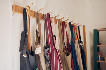 Image showing Clothing rack, apron and workshop of clothes hanging on a creative studio wall for art, style or design. Closeup of aprons or work equipment for artistic development on rack for business startup