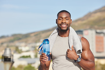 Image showing Portrait, fitness and water bottle with a sports black man or runner standing outdoor with a towel during exercise. Training, running and workout with a young male athlete outside for cardio