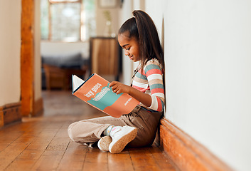 Image showing Little girl, book and reading on wooden floor for learning, education or story time relaxing at home with smile. Happy child smiling, sitting and enjoying books, read or stories at the house indoors