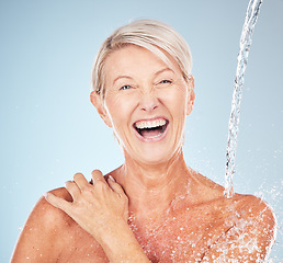 Image showing Happy, cleaning and portrait of a woman with a water splash isolated on a blue background in studio. Grooming, hygiene and face of an excited senior model with body and self care on a backdrop