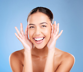 Image showing Woman, skincare and studio portrait with smile, happy and natural glow from cosmetics, self care or hands. Model, cosmetic beauty and self love with makeup aesthetic, shine or face by blue background