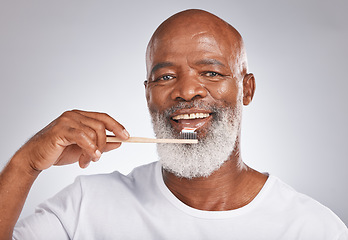 Image showing Portrait, black man and brushing teeth with toothbrush for dental wellness, healthy lifestyle or cleaning cosmetics in Nigeria. Happy male model, oral mouth care and mature smile on studio background