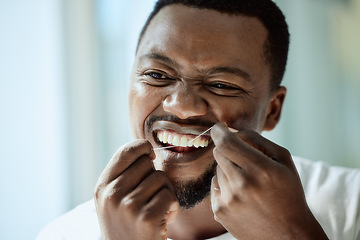 Image showing Health, beauty and teeth of black man with dental floss for morning oral hygiene routine with focus. Dental care, self care and wellness of person cleaning and checking teeth in bathroom mirror.