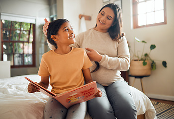 Image showing Family, book or learning and a girl reading in a bedroom with her mom playing with her hair in their home. Books, education and love with a mother and daughter bonding while sitting on a bed together