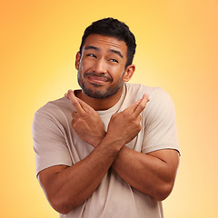 Image showing Fingers crossed, man and model with a orange studio background with hand sign for luck. Smile, hope and faith of a person with beard holding hands gesture for wish and optimism feeling hopeful