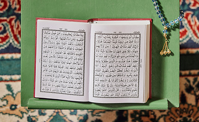 Image showing Quran, prayer beads and mosque with an open book and a rosary in an empty holy room or temple ready for praying. Islamic misbaha, tasbih or sibha and scripture in a muslim place of worship for eid