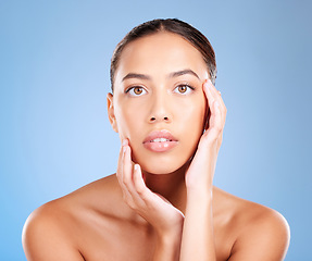 Image showing Face portrait, skincare and beauty of woman in studio on a blue background. Hands, natural cosmetics and makeup of young female model with healthy, smooth and glowing skin after facial treatment.