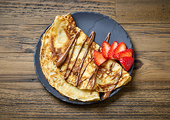 Image showing plate of crepes with strawberry and melted chocolate sauce