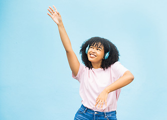 Image showing Wall, black woman and dance with smile, celebration and relax on blue studio background. African American female, lady and dancing with headphones, movement and excited with casual outfit on backdrop