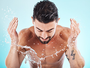 Image showing Skincare, water splash and man in a studio for a wellness, health and self care body routine. Cosmetics, hydration and male model with natural dermatology facial treatment isolated by blue background