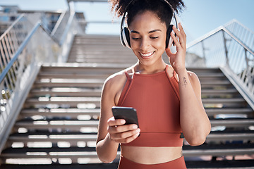 Image showing Fitness, music headphones and black woman with phone for social media in city. Sports, exercise and female athlete streaming song, radio or podcast on 5g mobile smartphone after training outdoors.