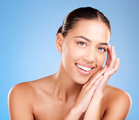 Image showing Woman, skincare and studio portrait with smile, happy and natural glow from cosmetics, self care or hands. Model, cosmetic beauty and self love with makeup aesthetic, shine or face by blue background