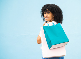 Image showing Back, portrait and black woman with bags, shopping and purchase expensive items with girl on blue studio background. Mockup, Jamaican female and customer with boutique clothes, retail and discount