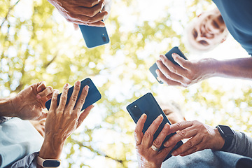 Image showing Fitness, group with smartphone in hands and running in park, technology low angle and check exercise mobile app. Elderly runner team outdoor with health, senior and phone for cardio sports motivation