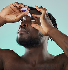 Image showing Black man, studio and eye drop for health vision, wellness and self care by blue backdrop for morning routine. African gen z model, eyes and product for healthcare, medicine and medical serum bottle