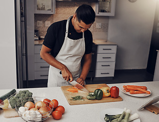 Image showing Cooking, food and vegetables with a man cutting ingredients in the kitchen on a wooden chopping board. Salad, health and diet with a male chef preparing a meal while standing alone in his home