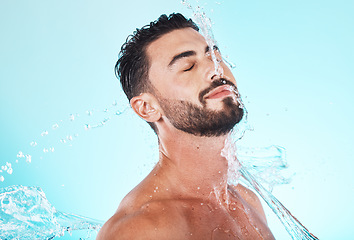 Image showing Water, splash and skincare with face of man for shower, self care and natural cosmetics. Luxury, hydration and refreshing with model for dermatology, wellness and cleaning in blue background studio