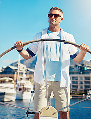 Image showing Yacht, sailing and travel with a mature man steering a boat on the ocean or sea during summer vacation or holiday. Water, freedom and blue sky with a handsome male sailor standing on a boat outdoor