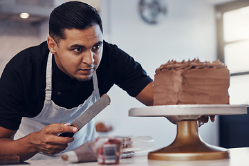 Image showing Baking, kitchen and man icing cake with chocolate frosting and piping bag in bakery with focus and skill. Sweets, small business and baker decorating dessert for birthday event and working from home.