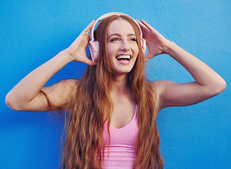 Image showing Music, headphones and blue background with a woman streaming or listening to audio for fun. Radio, internet and 5g with an attractive young female using wireless technology to listen to a song