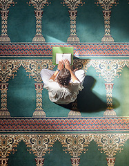 Image showing Religion, quran and Muslim man reading for spiritual education, learning worship and faith during ramadan. Islam, holy and above of an Islamic person with a book in a mosque for studying prayer