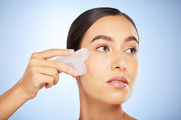 Image showing Skincare woman, crystal glow and gua sha for wellness, beauty and cosmetic health by blue background. Model, skin and self care with rose quartz, cosmetics and cleaning face for self love by backdrop