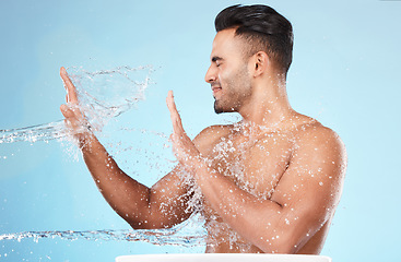 Image showing Body, water splash and skincare of man cleaning in studio isolated on a blue background. Hygiene, water drops and male model washing, bathing or grooming for healthy skin, facial wellness or beauty.