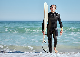 Image showing Portrait, man and surfer on beach, training and wet for competition, relax and summer break. Male, athlete and guy with surfboard, water or fun for fitness, practice or workout for wellness or health