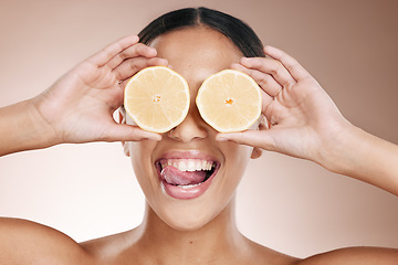 Image showing Woman face, tongue and lemon skincare hands on studio background in organic dermatology routine and healthcare wellness. Zoom, happy and fun beauty model and facial fruit, diet food and eyes product