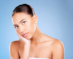 Image showing Face portrait, skincare and beauty of woman in studio on a blue background. Hands, natural cosmetics and makeup of young female model with healthy, smooth and glowing skin after facial treatment.