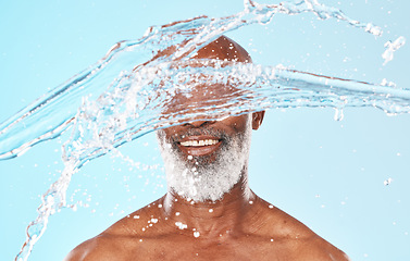 Image showing Happy black man, face and water splash in studio for cleaning, self care and headshot cosmetics on blue background. Shower, wellness and male beauty with water drops, healthy skincare and facial body