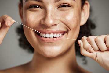 Image showing Woman portrait, dental floss and flossing teeth with smile for oral hygiene, health and wellness on studio background. Face of female happy about self care, healthcare and grooming for healthy mouth