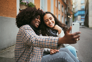 Image showing City, friends and women take selfie with phone and sitting on sidewalk laughing and happy together. Photo, video call and black woman with girl friend with urban fun and social media profile picture.