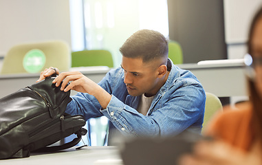 Image showing University student, man and backpack in a classroom for education, studying and learning at campus. Person in class searching for object in bag to learn and study at college, school or campus