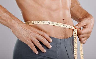 Image showing Man, body and tape measure on waist in studio on gray background. Health, fitness and male model with measuring tape for abdomen to track exercise training results, muscle goals or weight loss target