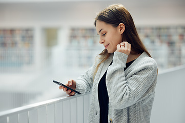 Image showing Woman, phone and smile for social media, networking or chatting in communication at a library. Happy female smiling for texting, research or browsing for books on smartphone at big book store or mall