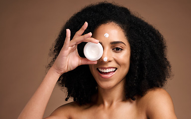 Image showing Face, skincare and black woman with cream container in studio on a brown background. Makeup cosmetics, portrait and female model apply facial lotion, product or moisturizer creme for healthy skin.