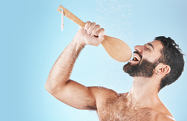 Image showing Bathroom, singing and washing with a man model in studio on a blue background using a loofah to sing. Water, showering and hygiene with a handsome male wet while cleaning for personal body care