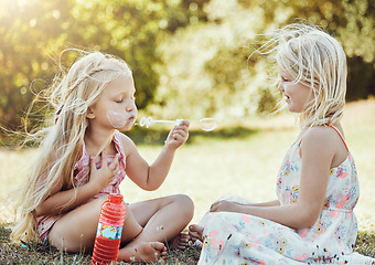 Image showing Nature, girls and friends blowing bubbles in a green garden being playful, happy and fun together. Happiness, holiday and sisters playing on the grass in an outdoor park in summer in Australia.
