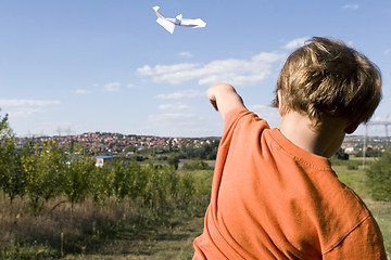 Image showing young boy flying a paper plane