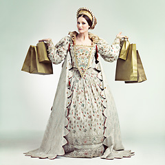 Image showing Fashion, queen and portrait of woman with shopping bags in studio isolated on a gray background. Royalty, sales deals or rich and wealthy female ruler holding luxury golden gifts after buying at mall