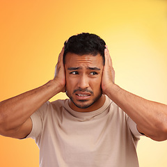 Image showing Scared, loud and man worried by his stress and covering his ears in fear of noise isolated against a studio orange background. Young, hispanic or guy frustrated by sound causing head pain or ache