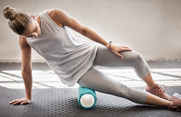 Image showing Fitness, physio massage and woman with roller on floor for leg tension and support in yoga workout at gym. Health, pilates and massaging for sports physiotherapy, girl on ground foam rolling muscle.