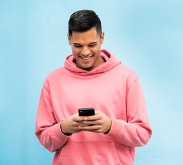 Image showing Happy man, fashion or phone typing on isolated blue background in Brazil city on social media, app or internet. Smile, person or student model on mobile communication technology by urban wall mock up