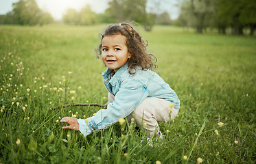 Image showing Girl child, smile and flowers in park, outdoor and learning for plants in backyard, field or woods. Young female kid, picking flower and portrait on grass lawn, spring or exploring ground by forest