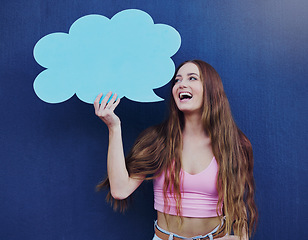 Image showing Happy woman holding a speech bubble with mockup space standing by a blue wall with a sign. Gen z, happiness and young female with a chat board with mock up or copy space for marketing or advertising.