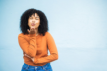 Image showing Portrait, kiss and woman flirting in studio for fun, playful and personality against a blue background. Black woman, blowing kiss and emoji for kissing, attraction and desire while standing isolated